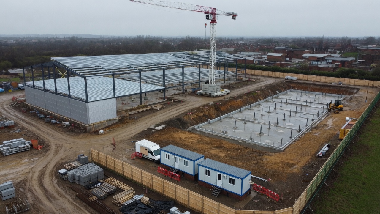 Aerial construction progress photograph showing cladding underway and foundations on the adjacent plot.